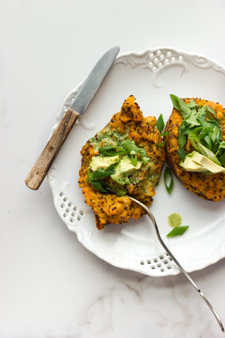 Vegan stuffed sweet potatoes with coconut curried quinoa, chickpeas and avocado cilantro sauce. Fully loaded with flavour. Gluten free.