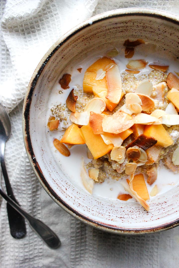 Creamy quinoa porridge with almond milk, persimmons and toasted coconut. A quick and easy gluten free vegan breakfast!