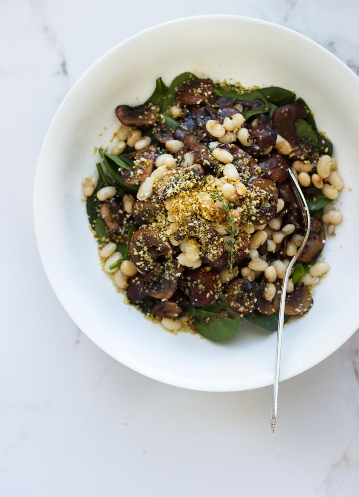 Warm Balsamic Mushroom Salad with Pine Nut Parmesan from The First Mess Cookbook. Loaded with spinach and navy beans. Vegan and Gluten Free.