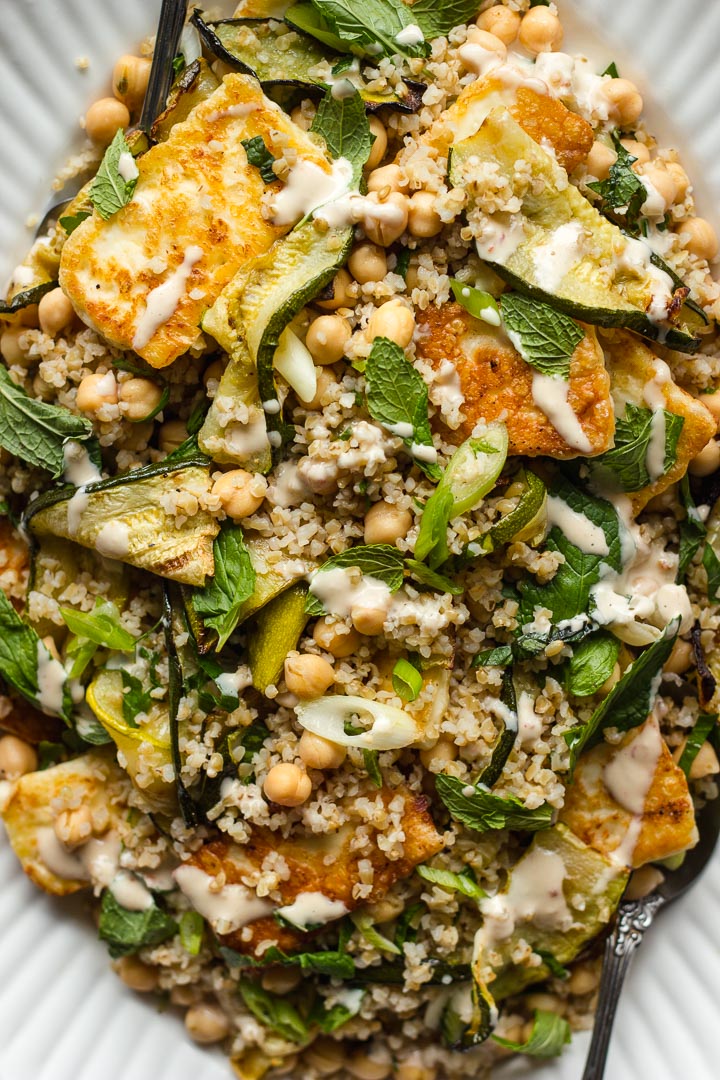 Grilled zucchini salad with halloumi, bulgur and chickpeas. Top with lots of fresh mint and a sweet and spicy tahini dressing. The ultimate summer salad.